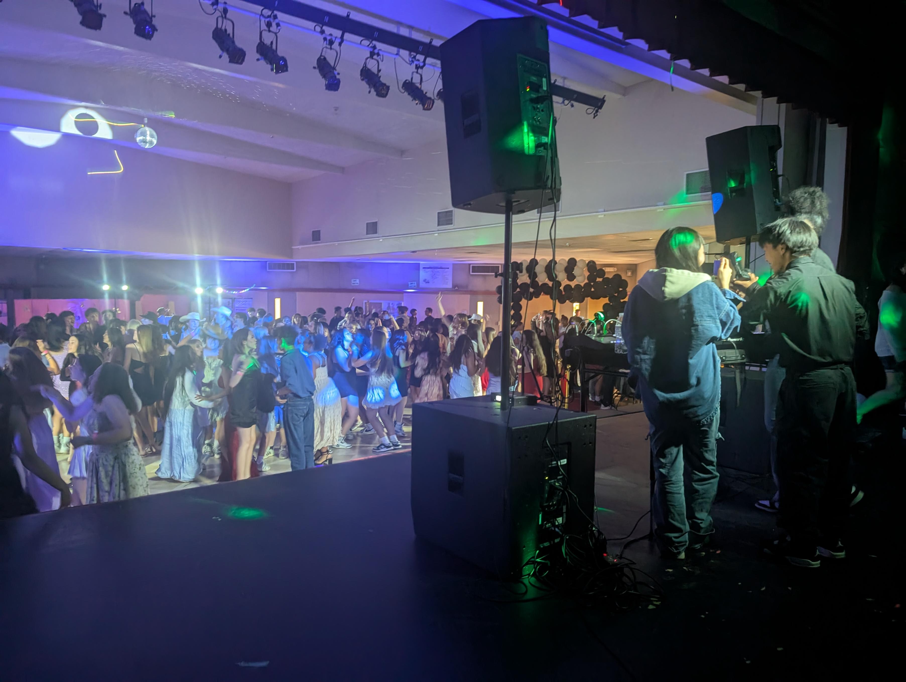 Student DJs providing live sound and lighting for a crowded high school dance
